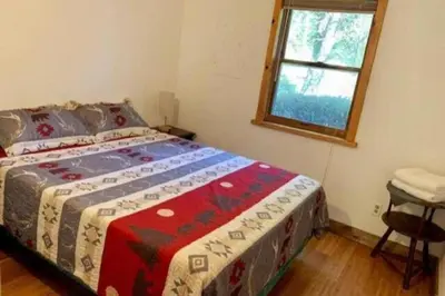 a bedroom with a bed with a colorful blanket on it at Spacious Cabin Rental next to Balsam Mountain in Upstate New York in Big Indian