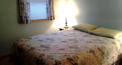 a bedroom with a bed with a lamp and a window at Spacious Cabin Rental next to Balsam Mountain in Upstate New York in Big Indian