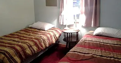 a bedroom with two beds and a window with a lamp at Spacious Cabin Rental next to Balsam Mountain in Upstate New York in Big Indian
