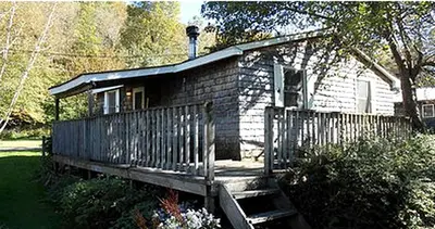 a small brick house with a porch and a fence at Family-Friendly Cabin Accommodation with Large Yard near Woodstock in Big Indian