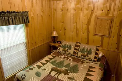 a bedroom with a bed in a log cabin at Deluxe Vacation Cabin Rentals in the Adirondacks near Saratoga Springs, New York in Corinth