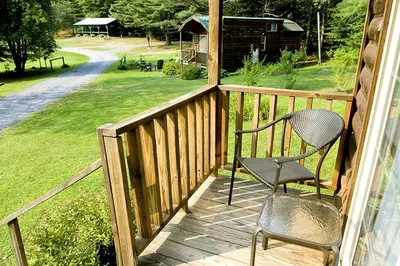 a chair on a porch with a view of a yard at Deluxe Vacation Cabin Rentals in the Adirondacks near Saratoga Springs, New York in Corinth