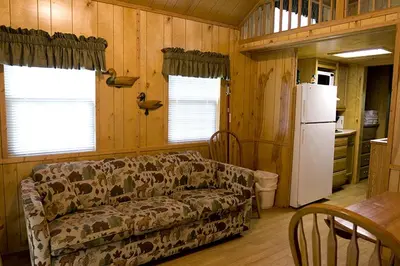 a living room with a couch and a refrigerator at Deluxe Vacation Cabin Rentals in the Adirondacks near Saratoga Springs, New York in Corinth