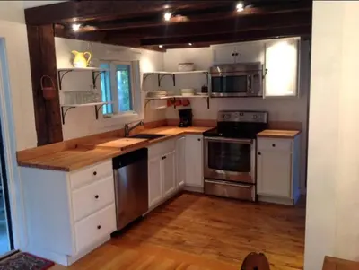 a kitchen with white cabinets and stainless steel appliances at Secluded Cabin with Gorgeous Views near Stockbridge in the Berkshires of Massachusetts in Stockbridge