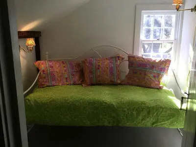 a bedroom with a green bed with pillows and a window at Secluded Cabin with Gorgeous Views near Stockbridge in the Berkshires of Massachusetts in Stockbridge