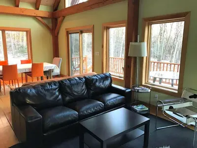 a living room with a black leather couch and a table at Beautiful Two-Bedroom Cabin Rental Set in the Forests of the Berkshires, Massachusetts
