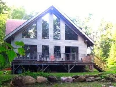 a large house with a porch and a balcony at Beautiful Two-Bedroom Cabin Rental Set in the Forests of the Berkshires, Massachusetts