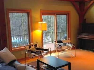 a living room with a couch and a table and windows at Beautiful Two-Bedroom Cabin Rental Set in the Forests of the Berkshires, Massachusetts