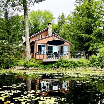 a house with a deck on the side of a lake at Lakefront Cabin Getaway near Adirondack Mountains in Salisbury, New York