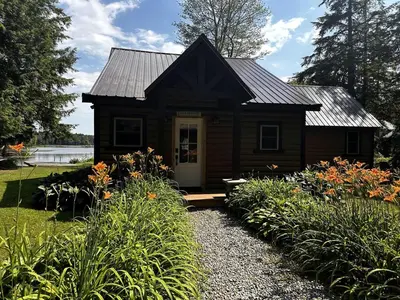 a small house with a porch in a garden at Lakefront Cabin Getaway near Adirondack Mountains in Salisbury, New York