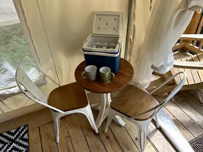 a table with a cooler and two mugs on it at Luxurious Safari Tent in Cooperstown, NY - Perfect Glamping Spot for a Romantic Getaway in Cooperstown