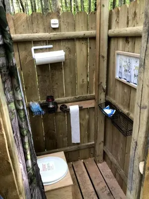a bathroom with a toilet in a wooden fence at Luxurious Safari Tent in Cooperstown, NY - Perfect Glamping Spot for a Romantic Getaway in Cooperstown
