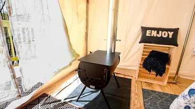 a small stove in a room with a tent at Luxurious Safari Tent in Cooperstown, NY - Perfect Glamping Spot for a Romantic Getaway in Cooperstown