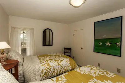a bedroom with two beds and a picture of cows on the wall at Riverfront Cabin with Beautiful Views of Housatonic River in Great Barrington, Massachusetts in Housatonic