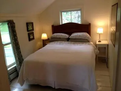 a bedroom with a large white bed with two lamps at Riverfront Cabin with Beautiful Views of Housatonic River in Great Barrington, Massachusetts in Housatonic