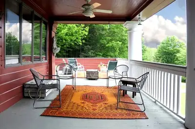 a screened in porch with chairs and a rug at Impressive Cabin with a Pool and Hot Tub Ideal for Weekend Getaways in the Catskills in Hunter