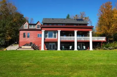 a large red house with a green field in front of it at Impressive Cabin with a Pool and Hot Tub Ideal for Weekend Getaways in the Catskills in Hunter