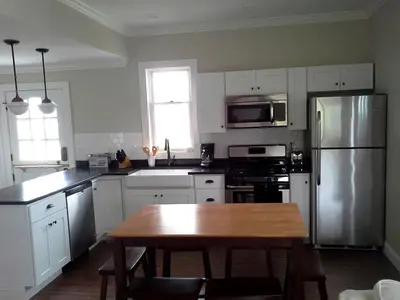 a kitchen with a table and a stainless steel refrigerator at Spacious Guest Cottage Rental on Lake in Berkshires, Massachusetts in Lanesborough