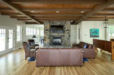 a living room with a couch and a stone fireplace at Four-Bedroom Luxury House Rental on Pontoosuc Lake in the Berkshires in Lanesborough
