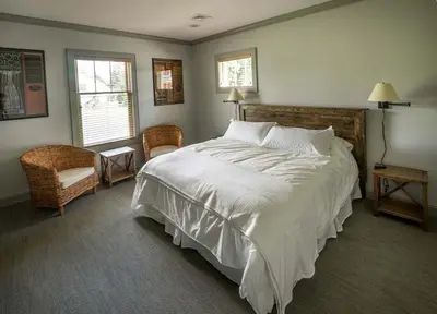 a bedroom with a large white bed and a chair at Four-Bedroom Luxury House Rental on Pontoosuc Lake in the Berkshires in Lanesborough