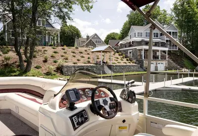 a boat on the water in front of a house at Four-Bedroom Luxury House Rental on Pontoosuc Lake in the Berkshires in Lanesborough