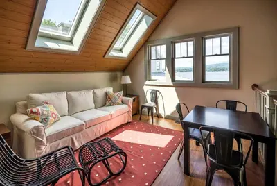 a living room with a couch and a table and windows at Impressive Family-Friendly Lake Cottage in Berkshires, Massachusetts in Lanesborough