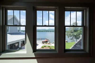 a room with three windows looking out at the water at Impressive Family-Friendly Lake Cottage in Berkshires, Massachusetts in Lanesborough