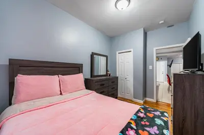 a bedroom with a pink bed and a television at Newark 3BR Gem - Near NYC - & Attractions in Newark