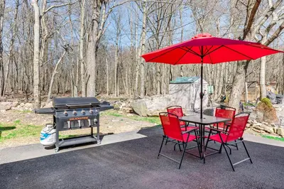 a table and chairs with a red umbrella and a grill at Poconos Hot Tub Haven! 14 Mi to Camelback Resort in Pocono Country Place