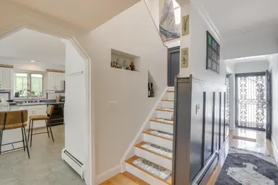 a staircase in a home with white walls and a kitchen at Lake Carmel Access Waterfront Home with Deck! in Carmel