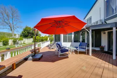 a patio with a red umbrella on a deck at Lake Carmel Access Waterfront Home with Deck! in Carmel