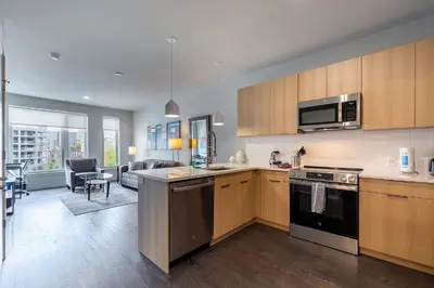 a kitchen with wooden cabinets and a living room at Luxury Apt Downtown in White Plains