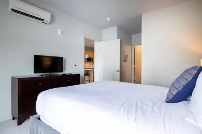 a bedroom with a white bed and a flat screen tv at Luxury Apt Downtown in White Plains