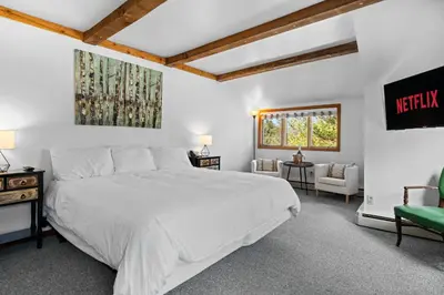 a bedroom with a large white bed and two chairs at Jessie's Harvest House in Tannersville