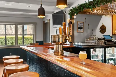 a bar with wooden stools and a drink at Jessie's Harvest House in Tannersville
