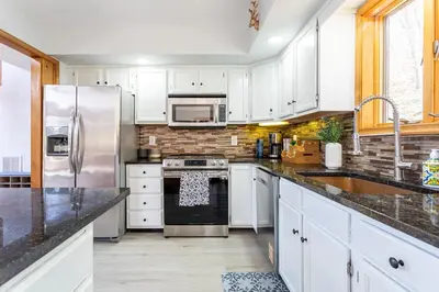 a kitchen with white cabinets and stainless steel appliances at Beautiful Modern Lodge! Game Room in Saw Creek