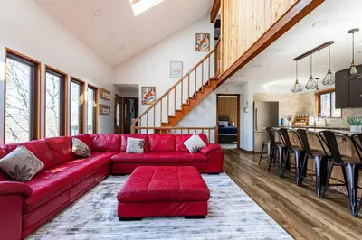 a living room with a red couch and a kitchen at Modern Rustic Lodge! Game Room in Saw Creek