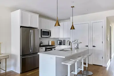a kitchen with white cabinets and a stainless steel refrigerator at Hoboken Loft Hideaway - walk to PATH in Hoboken