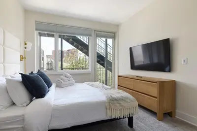 a bedroom with a bed and a flat screen tv at Hoboken Loft Hideaway - walk to PATH in Hoboken