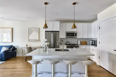 a kitchen with white cabinets and a large white island at Hoboken Loft Hideaway - walk to PATH in Hoboken