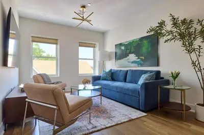 a living room with a blue couch and chairs at Bright 3BR Loft • Hoboken Gem in Hoboken