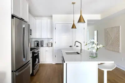 a kitchen with white cabinets and a stainless steel refrigerator at Sunny 2BR Loft • Work Relax Minutes to NYC in Hoboken