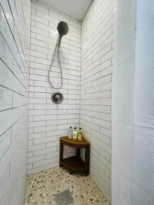 a shower in a white tiled bathroom with a wooden table at High-View Catskills Cabin in Margaretville