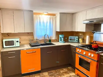 a kitchen with orange and gray cabinets and appliances at High-View Catskills Cabin in Margaretville