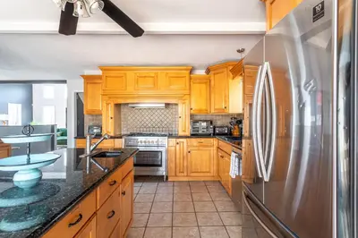 a kitchen with wooden cabinets and a stainless steel refrigerator at Mahogany Sun Hot Tub Theater Room Fire Pit in East Stroudsburg