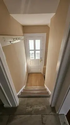 an empty hallway with a white door and stairs at The Heart of Hicksville House in Hicksville