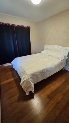 a large bed in a room with a wooden floor at The Heart of Hicksville House in Hicksville