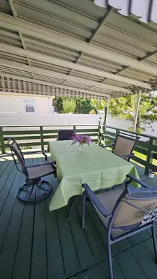 a green table and chairs on a wooden deck at The Heart of Hicksville House in Hicksville