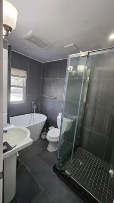 a bathroom with a tub and a toilet and a shower at The Heart of Hicksville House in Hicksville