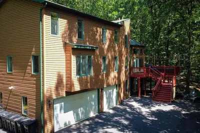 a house with a deck on the side of it at Twin Pines Retreat Hot Tub Theater Room Fire in East Stroudsburg